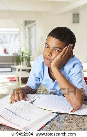 Picture - Fed Up Boy Doing Homework In Kitchen. Fotosearch