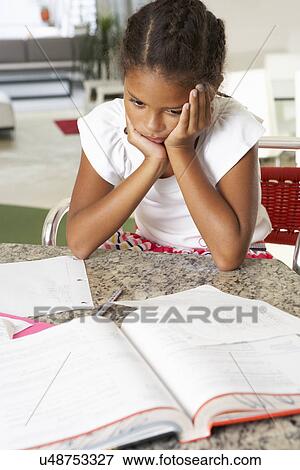 Stock Photo - Fed Up Girl Doing Homework In Kitchen. Fotosearch