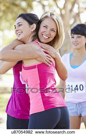 Stock Image - Female Runners Congratulating One Another After Race. Fotosearch