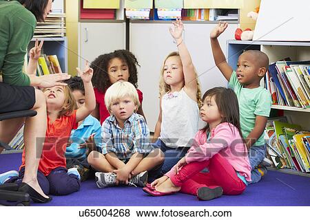 Stock Photo - Group of Elementary Pupils In Classroom Answering Question. Fotosearch
