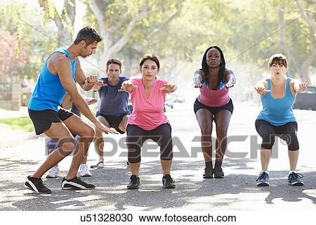 Stock Image - Group Of People Exercising Street With Personal Trainer. Fotosearch
