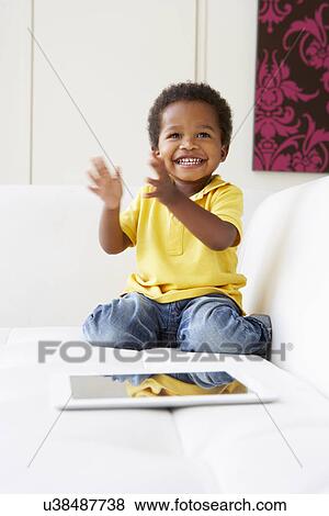 Happy Boy On Sofa Playing With Digital Tablet View Large Photo Image Stock Photo - Happy Boy On Sofa Playing With Digital Tablet. Fotosearch