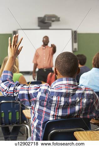 Stock Photo - Male Pupil Raising Hand In Class. Fotosearch