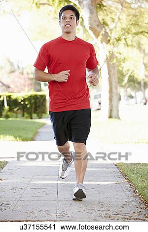 Stock Image - Male Runner Exercising On Suburban Street. Fotosearch
