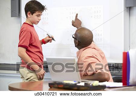 Stock Image - Male Student Writing Answer On Whiteboard. Fotosearch