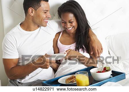 Stock Image - Man Bringing Woman Breakfast In Bed On Celebration Day. Fotosearch
