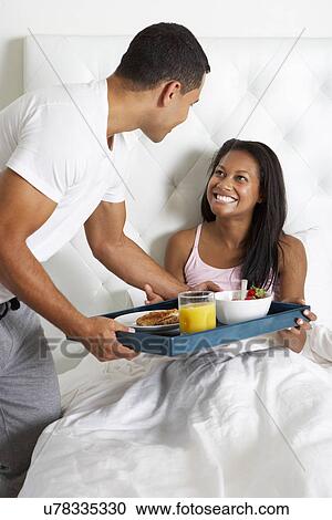 Stock Image - Man Bringing Woman Breakfast In Bed On Tray. Fotosearch
