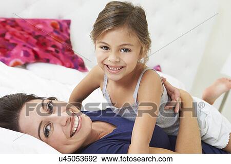 Stock Image - Mother And Daughter Lying In Bed Together. Fotosearch