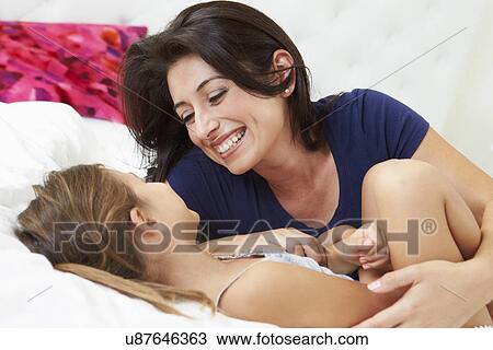 Stock Image - Mother And Daughter Lying In Bed Together. Fotosearch