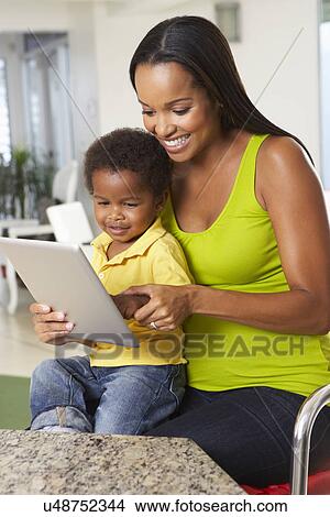 Picture - Mother And Son Using Digital Tablet In Kitchen Together. Fotosearch