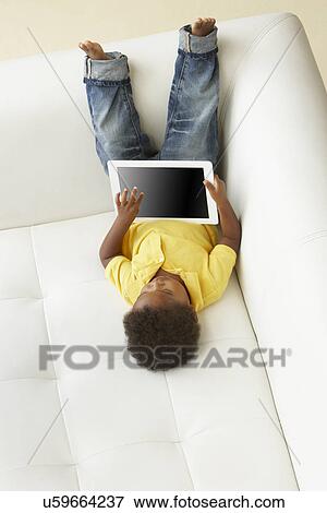Overhead View Of Boy On Sofa Playing With Digital Tablet View Large Photo Image Stock Photo - Overhead View Of Boy On Sofa Playing With Digital Tablet. Fotosearch