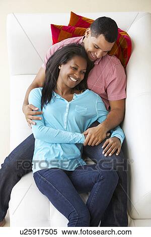 Stock Photography - Overhead View Of Couple Relaxing On Sofa Watching Television. Fotosearch