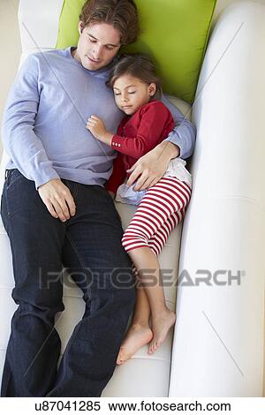 Stock Photography - Overhead View Of Father And Daughter Relaxing On Sofa. Fotosearch