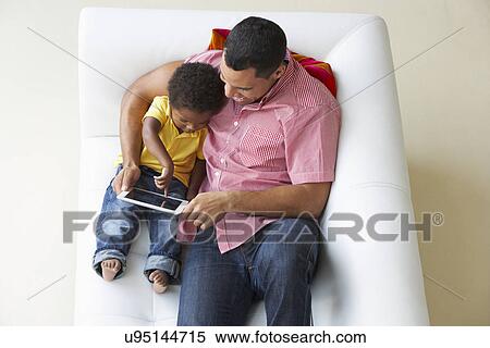 Overhead View Of Father And Son On Sofa Using Digital Tablet View Large Photo Image Stock Photography - Overhead View Of Father And Son On Sofa Using Digital Tablet. Fotosearch