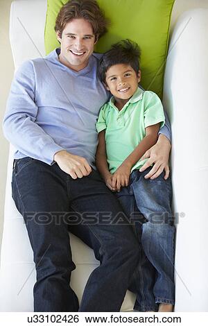 Stock Photograph - Overhead View Of Father And Son Relaxing On Sofa. Fotosearch
