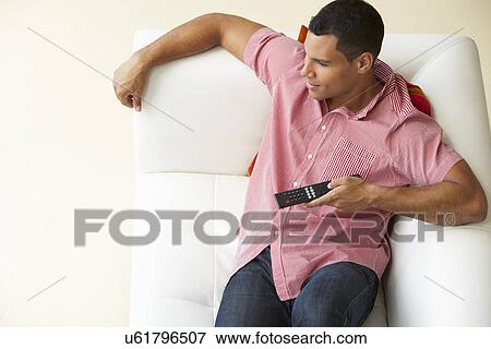 Stock Photo - Overhead View Of Man Relaxing On Sofa Watching Television. Fotosearch