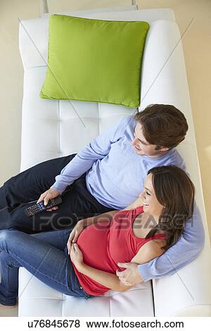 Stock Photo - Overhead View Of Man Relaxing On Sofa With Pregnant Wife . Fotosearch