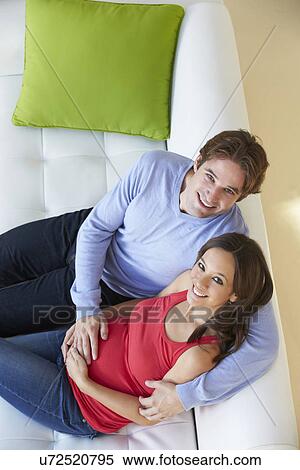 Overhead View Of Man Watching TV On Sofa With Pregnant Wife View Large Photo Image Stock Photography - Overhead View Of Man Watching TV On Sofa With Pregnant Wife . Fotosearch
