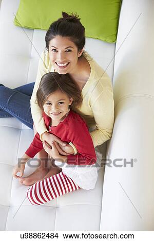 Picture - Overhead View Of Mother And Daughter Relaxing On Sofa. Fotosearch