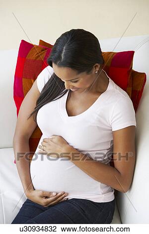 Stock Image - Overhead View Of Pregnant Woman Relaxing On Sofa. Fotosearch