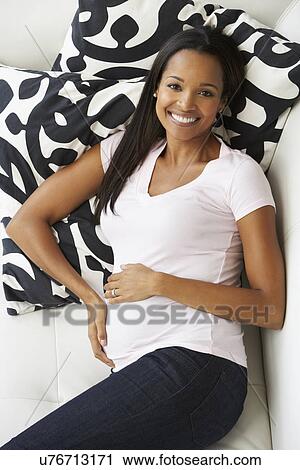 Stock Image - Overhead View Of Pregnant Woman Relaxing On Sofa. Fotosearch