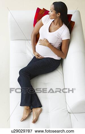 Stock Photo - Overhead View Of Pregnant Woman Relaxing On Sofa. Fotosearch