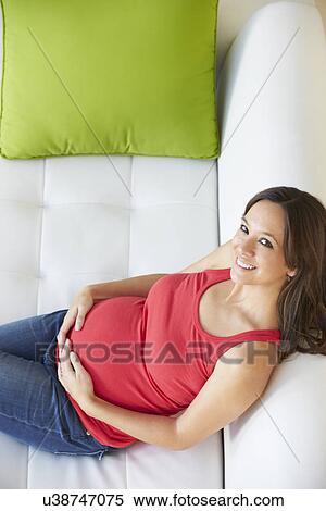 Stock Photography - Overhead View Of Pregnant Woman Relaxing On Sofa. Fotosearch