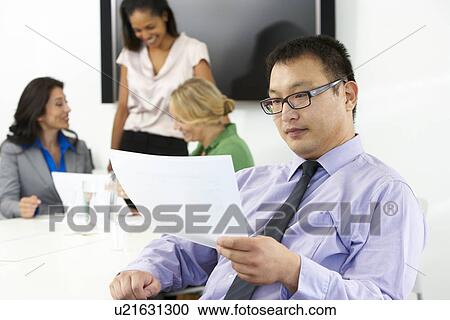 Stock Image - Portrait Of Businessman In Boardroom With Colleagues. Fotosearch