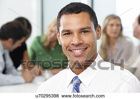 Stock Photo - Portrait Of Businessman Sitting At Boardroom Table. Fotosearch