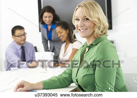 Stock Photography - Portrait Of Businesswoman In Boardroom With Colleagues. Fotosearch