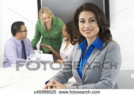 Stock Photography - Portrait Of Businesswoman In Boardroom With Colleagues. Fotosearch