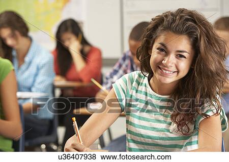 Stock Photo - Portrait Of Female Pupil Studying At Desk In Classroom. Fotosearch