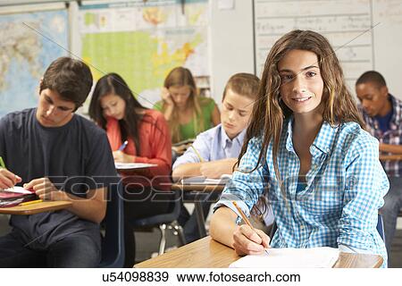 Stock Photo - Portrait Of Female Pupil Studying At Desk In Classroom. Fotosearch