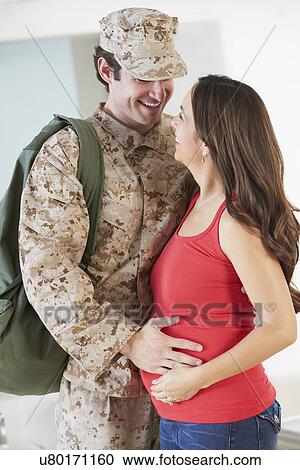 Stock Image - Pregnant Wife Greeting Military Mother Home On Leave. Fotosearch