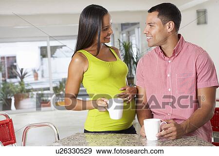 Stock Photo - Pregnant Woman And Husband Having Breakfast In Kitchen. Fotosearch