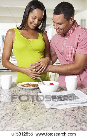 Stock Photography - Pregnant Woman And Husband Having Breakfast In Kitchen. Fotosearch