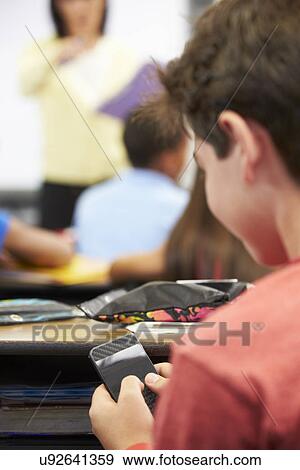 Pupil Sending Text Message On Mobile Phone In Class View Large Photo Image Stock Photo - Pupil Sending Text Message On Mobile Phone In Class. Fotosearch
