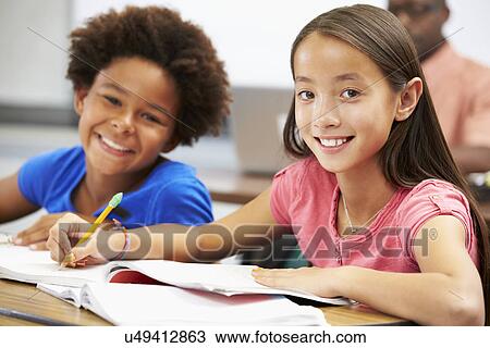 Stock Image - Pupils Studying At Desks In Classroom. Fotosearch