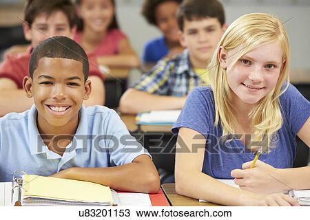 Stock Image - Pupils Studying At Desks In Classroom. Fotosearch