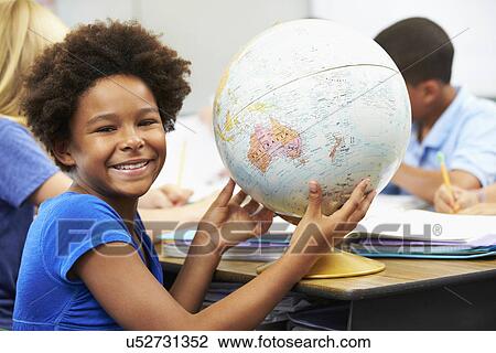 Stock Image - Pupils Studying Geography In Classroom. Fotosearch