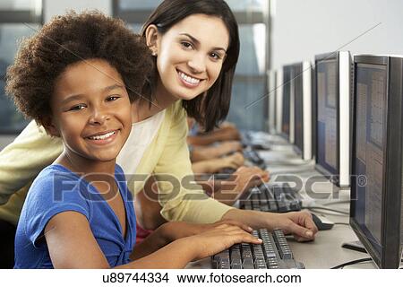 Teacher Helping Elelmentary Students Working At Computers View Large Photo Image Picture - Teacher Helping Elelmentary Students Working At Computers . Fotosearch