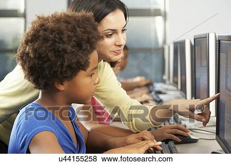 Stock Photo - Teacher Helping Elelmentary Students Working At Computers . Fotosearch