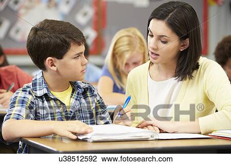 Teacher Helping Pupils Studying At Desks In Classroom View Large Photo Image Stock Image - Teacher Helping Pupils Studying At Desks In Classroom. Fotosearch