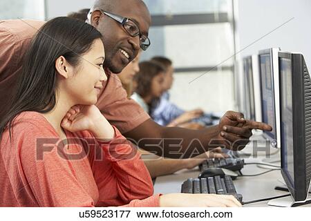 Teacher Helping Students Working At Computers In Classroom View Large Photo Image Stock Photo - Teacher Helping Students Working At Computers In Classroom. Fotosearch