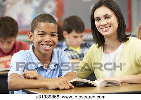Stock Photography - Teacher Reading With Male Pupil In Class. Fotosearch