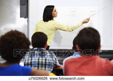 Stock Photograph - Teacher Standing In Class Using Interactive Whiteboard. Fotosearch