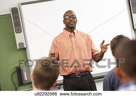 Teacher Talking To Class Standing In Front Of Whiteboard View Large Photo Image Stock Photograph - Teacher Talking To Class Standing In Front Of Whiteboard. Fotosearch