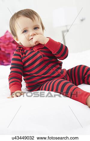 Stock Image - Toddler Sitting On Bed Wearing Pajamas. Fotosearch