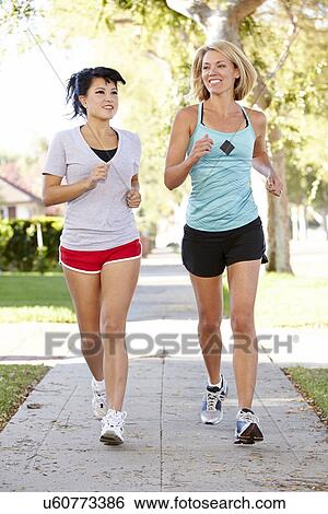 Stock Photograph - Two Female Runners Exercising On Suburban Street. Fotosearch