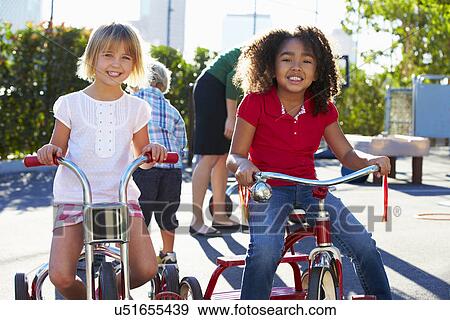 Two Girls Riding Tricycles In Playground View Large Photo Image Stock Photo - Two Girls Riding Tricycles In Playground. Fotosearch